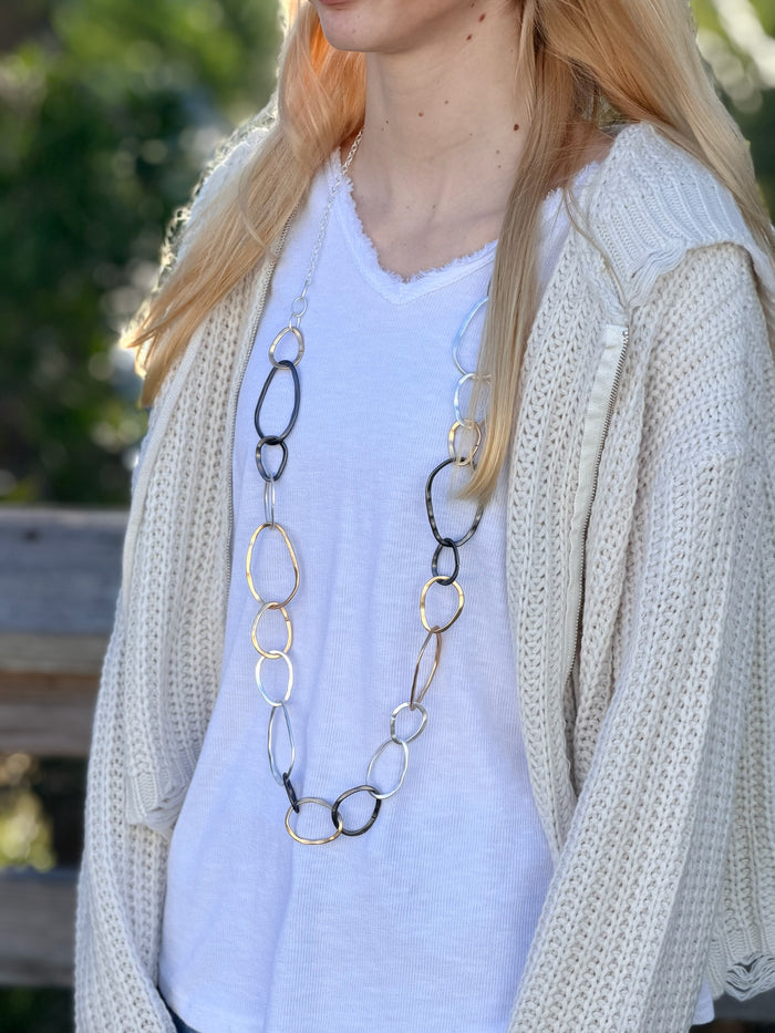 Person wearing a long necklace with interlocking rings outdoors