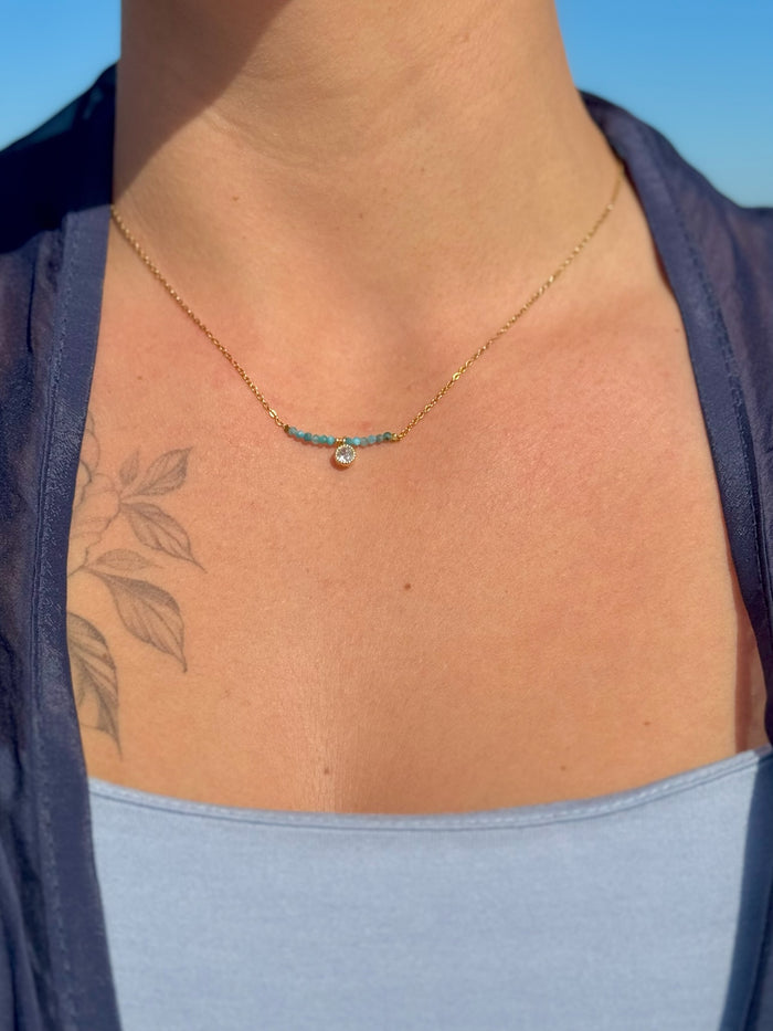 Model wearing Ava Apatite Stainless Steel Necklace featuring a blue apatite bead bar and a small crystal charm at the collarbone.