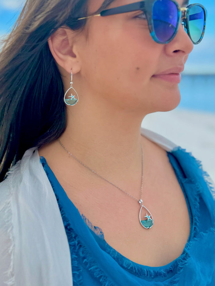 Woman wearing blue sunglasses and turquoise jewelry with a beach background