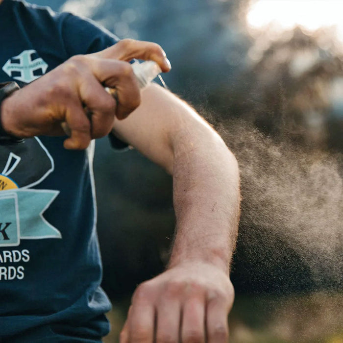 Lifestyle image of Lifesytems expedition sensitive DEET free insect repellent spray being used on a mans arm whilst outdoors