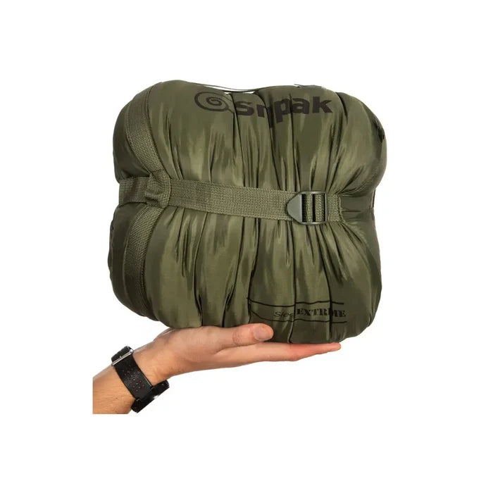 Studio shot on a white background of a Snugpak Sleeper Extreme sleeping bag packed in its compression sack in the palm of someones hand