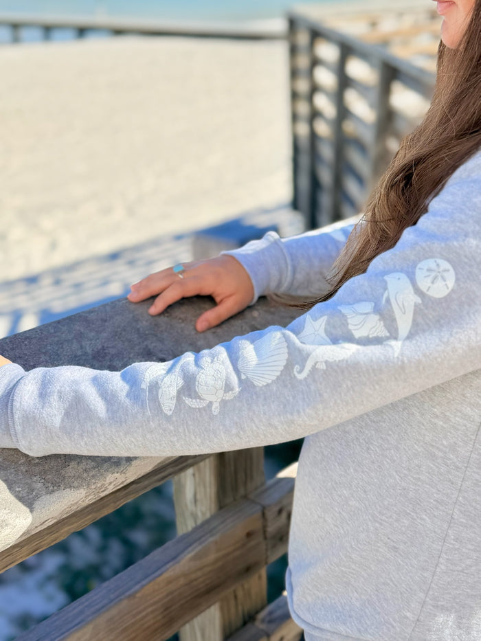 Woman wearing sea life icons on sleeve of hoodie overlooking the beach