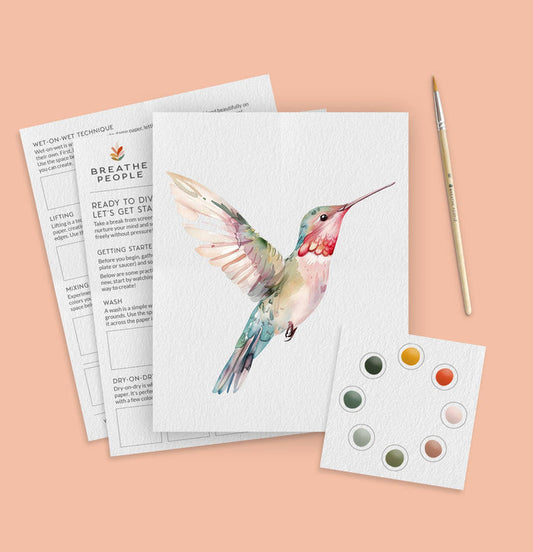 Artistic depiction of a hummingbird on a painting paper with a paintbrush and color swatches on a peach background