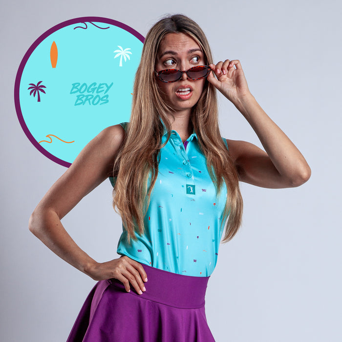 A woman in the Beach - Women's Polo, turquoise and sleeveless, pairs it with a purple athletic skirt as she lifts her sunglasses in surprise. Behind her is a round BOGEY BROS graphic with palm trees and abstract shapes on a light background.