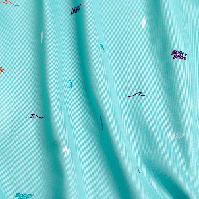 The Beach - Women's Polo features aqua blue fabric with scattered wave and palm tree prints, plus "BOGEY BROS" and "BAD" in various colors. Its moisture-wicking material keeps you comfortable as folds catch the light.