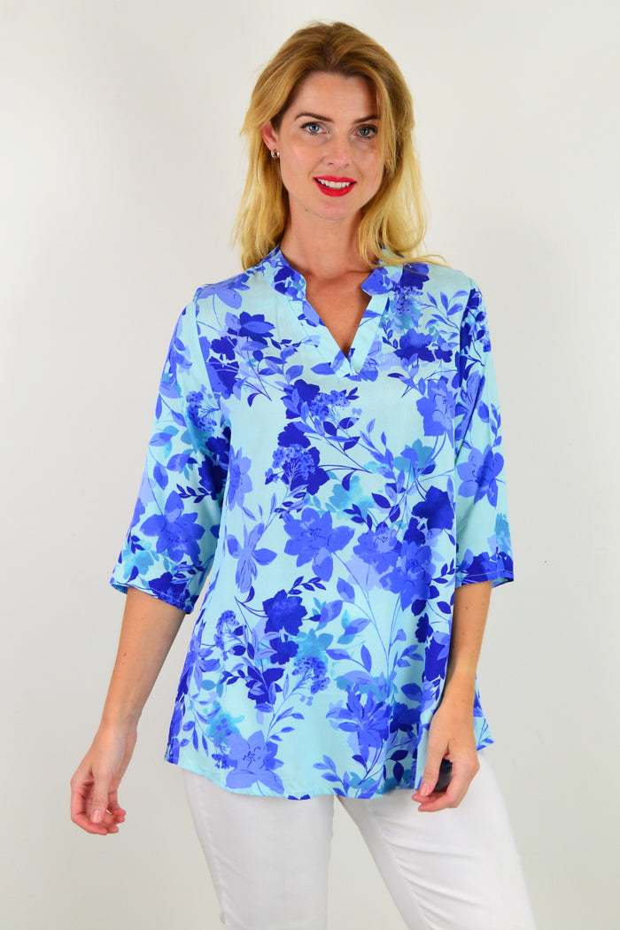 Blue floral tunic top from I Love Tunics with vibrant colorful flower patterns and a relaxed fit, shown on a hanger.
