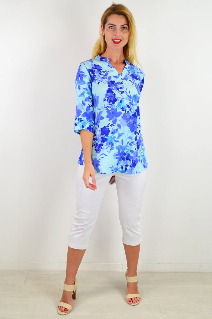 Blue floral tunic top by I Love Tunics featuring a colorful pattern and relaxed fit, shown hanging on a white background.