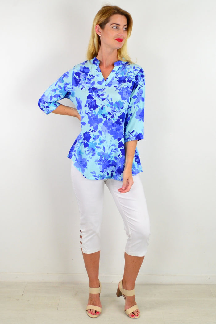 Blue floral tunic top by I Love Tunics featuring a vibrant pop of color and lightweight fabric, shown on a hanger.
