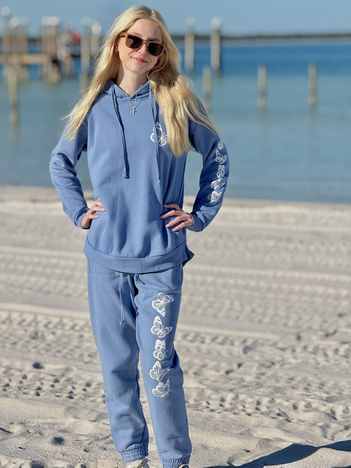 Women’s butterfly pullover hoodie with chest butterfly graphic, butterfly sleeve design, drawstring hood and ribbed trim at Ardor Boutique.