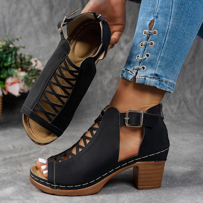 Black open-toe sandals with brown soles worn by a person in blue jeans.