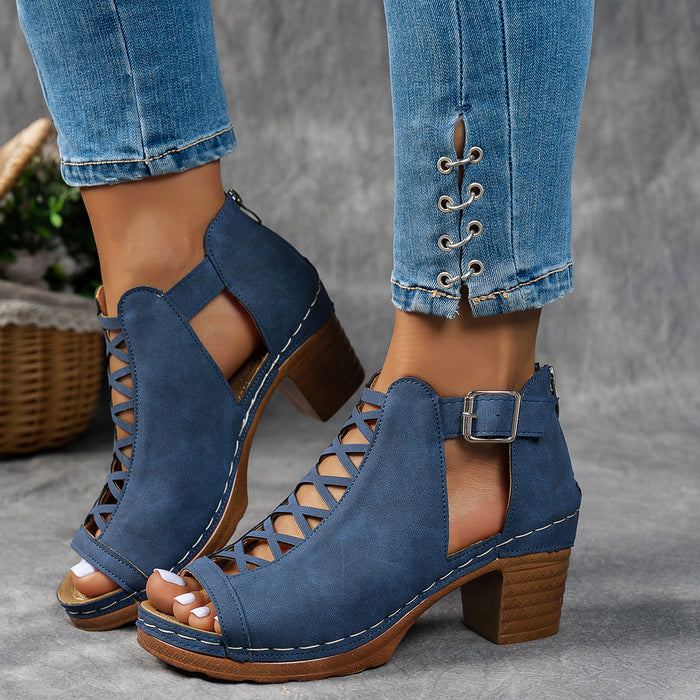 Blue open-toe sandals with brown soles worn with rolled-up jeans on a gray background