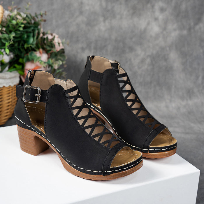 Black open-toe sandals with wooden block heels on a white surface with a gray background.