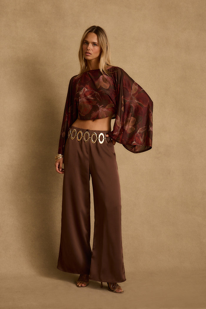 Mulberry floral mesh crop top with wide draped sleeves styled over brown wide-leg pants.
