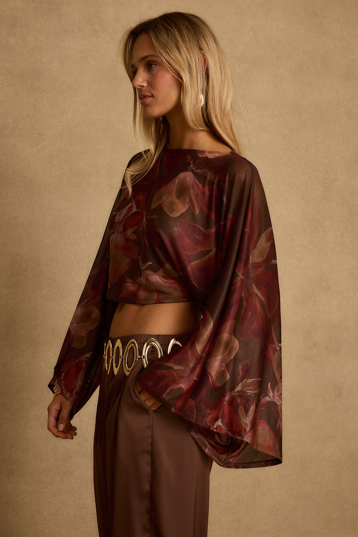 Side view of mulberry floral mesh crop top with wide flared sleeves over satin pants.