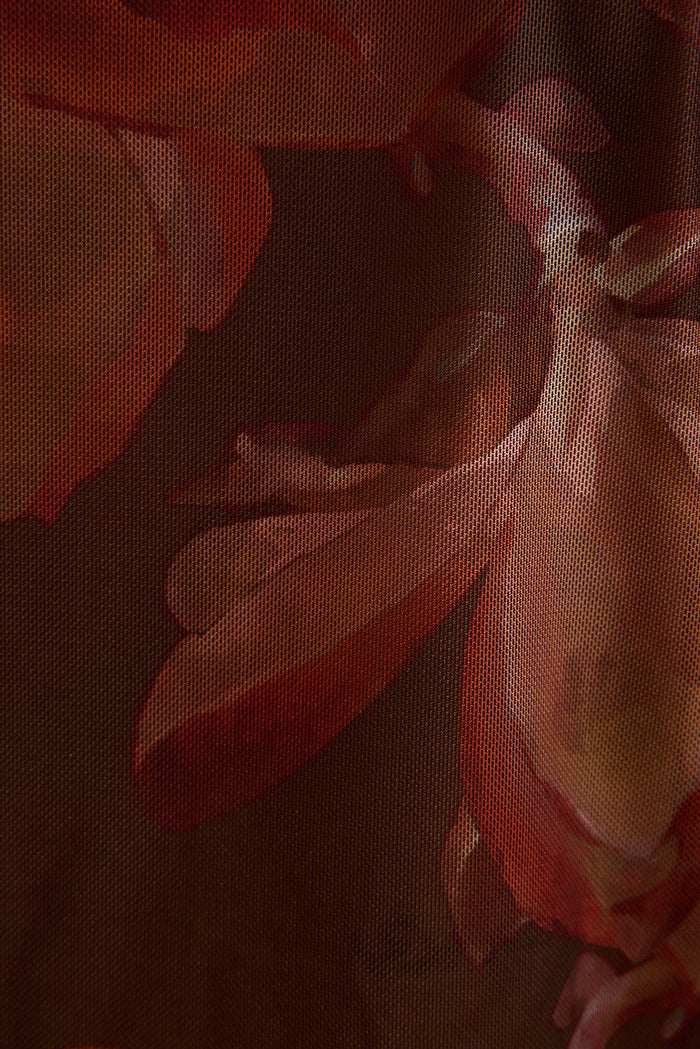 Close-up of sheer mulberry floral mesh fabric with rust and pink petal print.