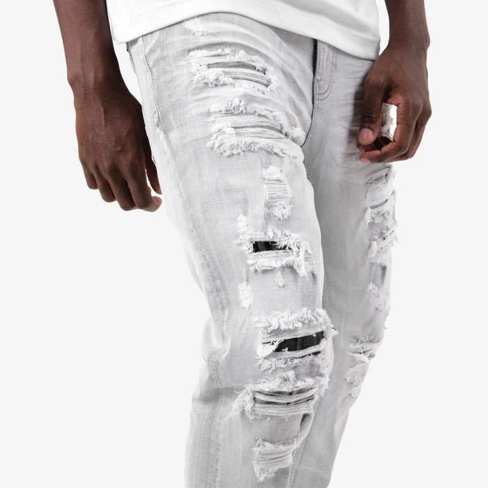 Copper Rivet Rip & Repair grey denim jeans showing distressed patch with copper rivets on front and back pockets.