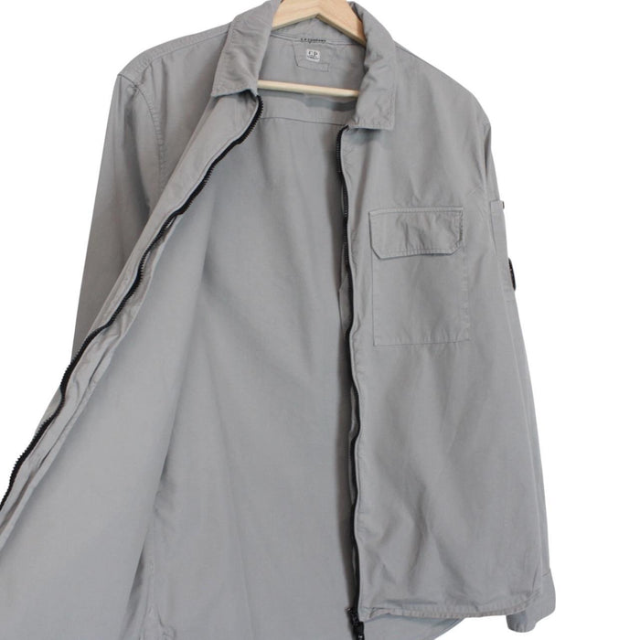 CP Company grey full zip overshirt jacket with lens detail and cotton material.