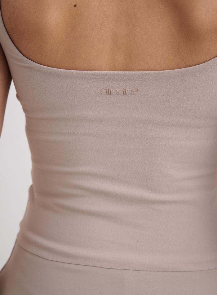 Lähikuva pehmeän Dark Clay Sense Singlet -topin selkäosasta ja sävyyn sointuvasta aim'n-logosta. [XS-174cm]