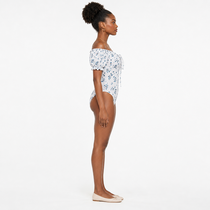 Side view of women's floral bodysuit showing the silhouette, puff sleeve shape and square neckline on a studio model.