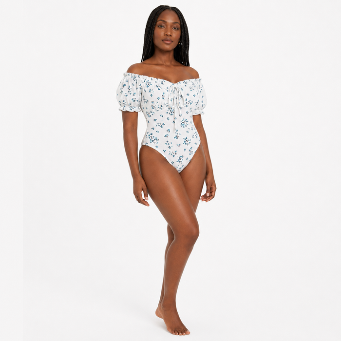 Three-quarter view of women's floral bodysuit highlighting the floral pattern, puff sleeves and square neckline.