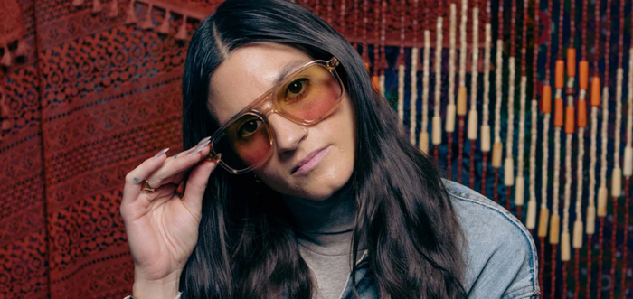 Model wearing Camp Eyewear Grateful Dead Forever unisex sunglasses featuring a translucent champagne frame, walnut wood temples, and yellow-to-pink gradient polarized lenses.