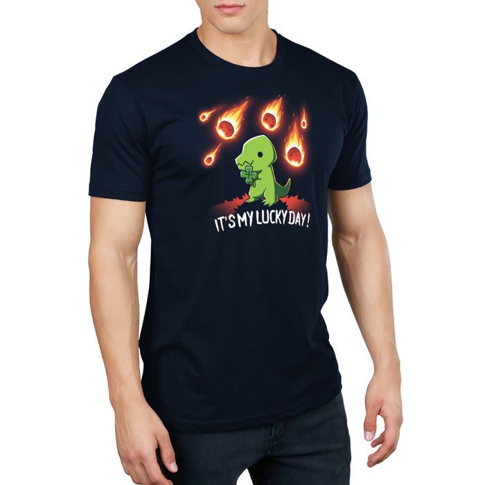 Premium Cotton T-shirt_TeeTurtle navy blue It's My Lucky Day featuring a dinosaur holding a four-leaf clover while meteors fall from the sky. The text below reads, "It's my lucky day!".