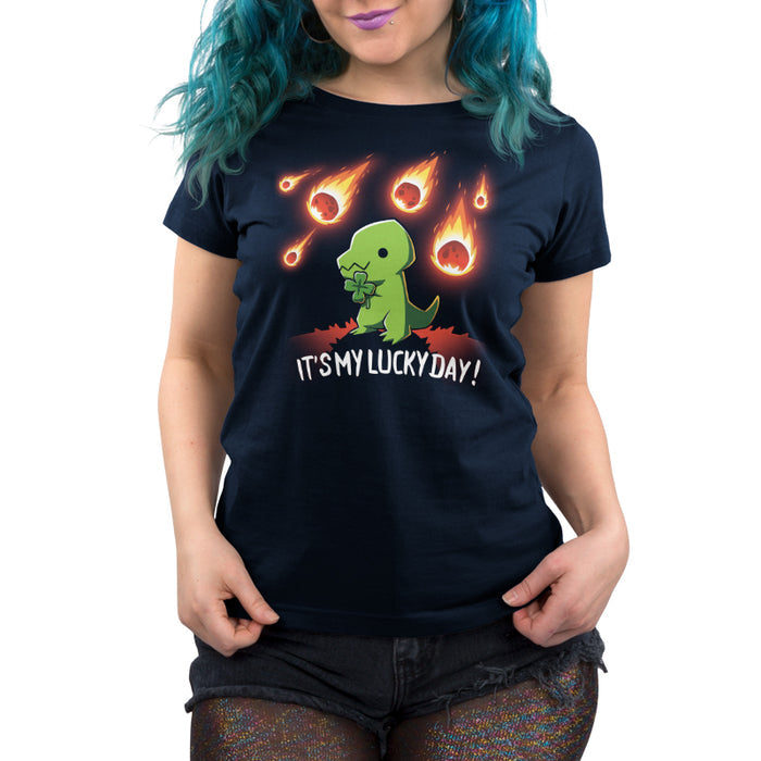 Premium Cotton T-shirt_TeeTurtle navy blue It's My Lucky Day featuring a dinosaur holding a four-leaf clover while meteors fall from the sky. The text below reads, "It's my lucky day!".