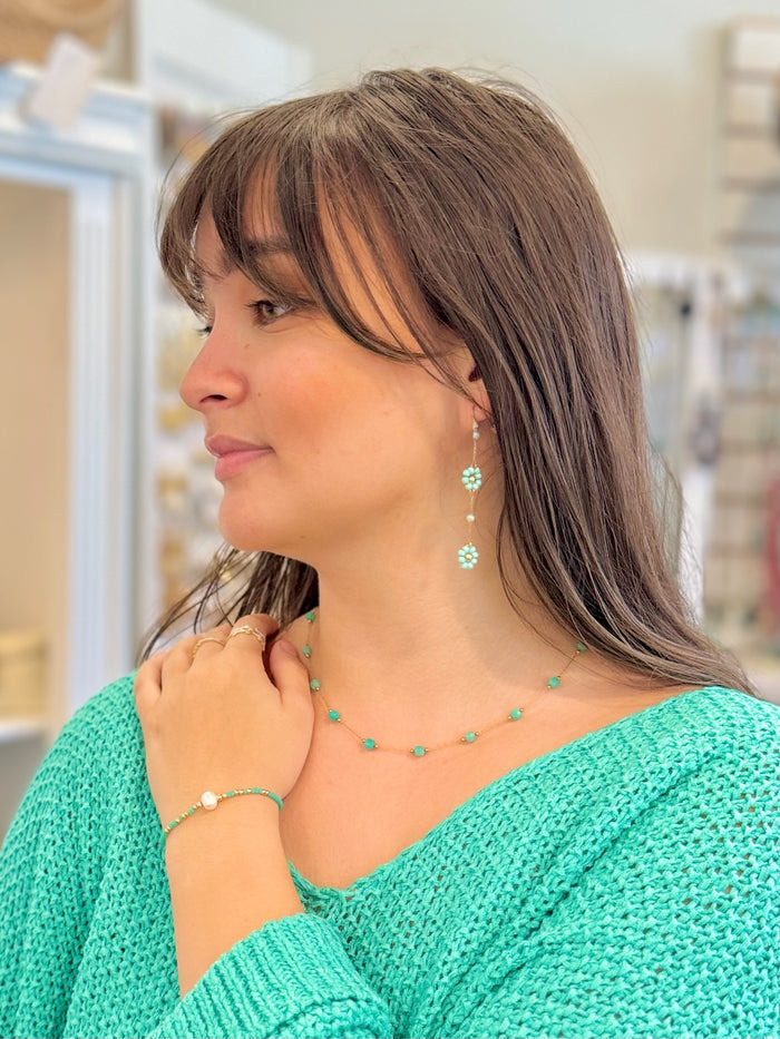 Woman wearing a green knitted sweater and turquoise jewelry in a store setting
