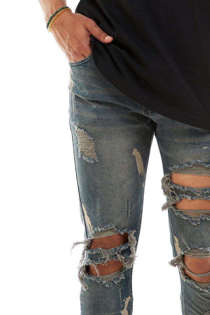 KDNK Destroyed Knee Ankle Zip Denim in steel blue, featuring distressed details and zip accents on a stylish denim jeans.