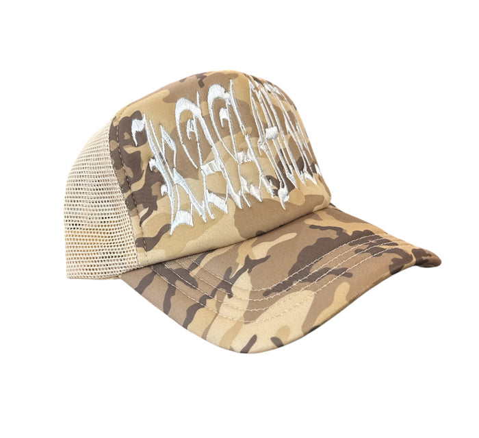KAAMIL KML ‘DAMAGED GOODS’ trucker hat in sand camo with distressed design and mesh back, casual outdoor style.