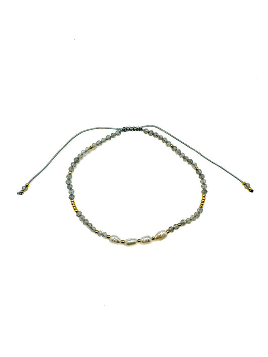 Adjustable bracelet featuring faceted gray labradorite gemstones, freshwater pearls, gold accent beads, and a sliding cord closure. Handmade with a delicate, coastal-inspired design perfect for everyday layering.
