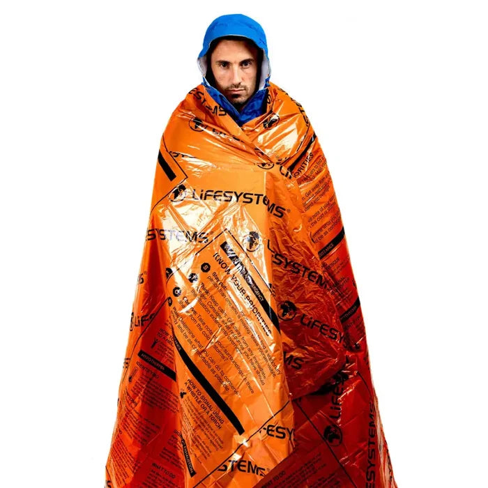 Person wrapped in an orange LifeSystems emergency heatshield thermal blanket on a white background