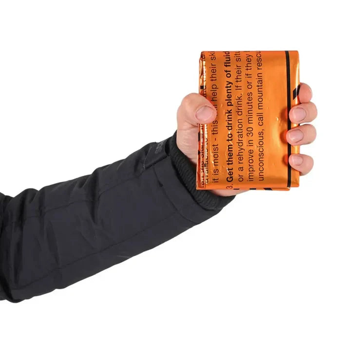 Hand holding a folded Lifesystems heatshield thermal blanket on a white background
