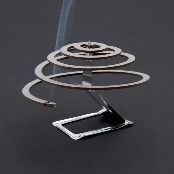 Lit single Lifesystems insect repellent coil on its burning stand on a grey background