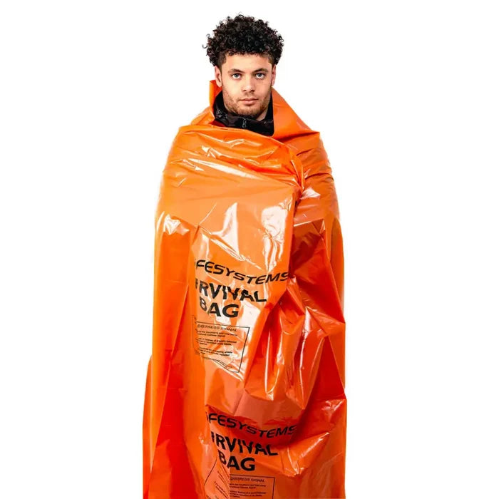 A man wrapped in a bright orange Lifesystems plastic survival bag, standing against a solid white background.