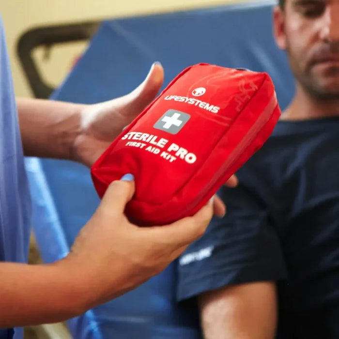 Health professional looking at a Lifesystems Sterile Pro First Aid Kit whilst treating a patient