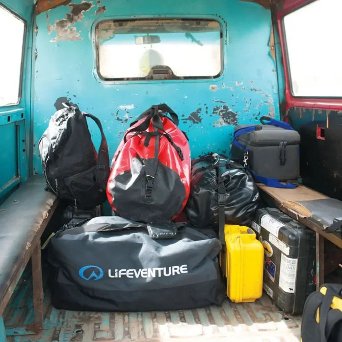 Back of an old van with various travel bags including a Lifeventure Expedition Duffle Bag 100 Litres in grey