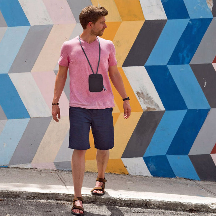 Lifestyle image of a man wearing a Lifeventure RFiD travel neck pouch around his neck whilst crossing the road in the sun