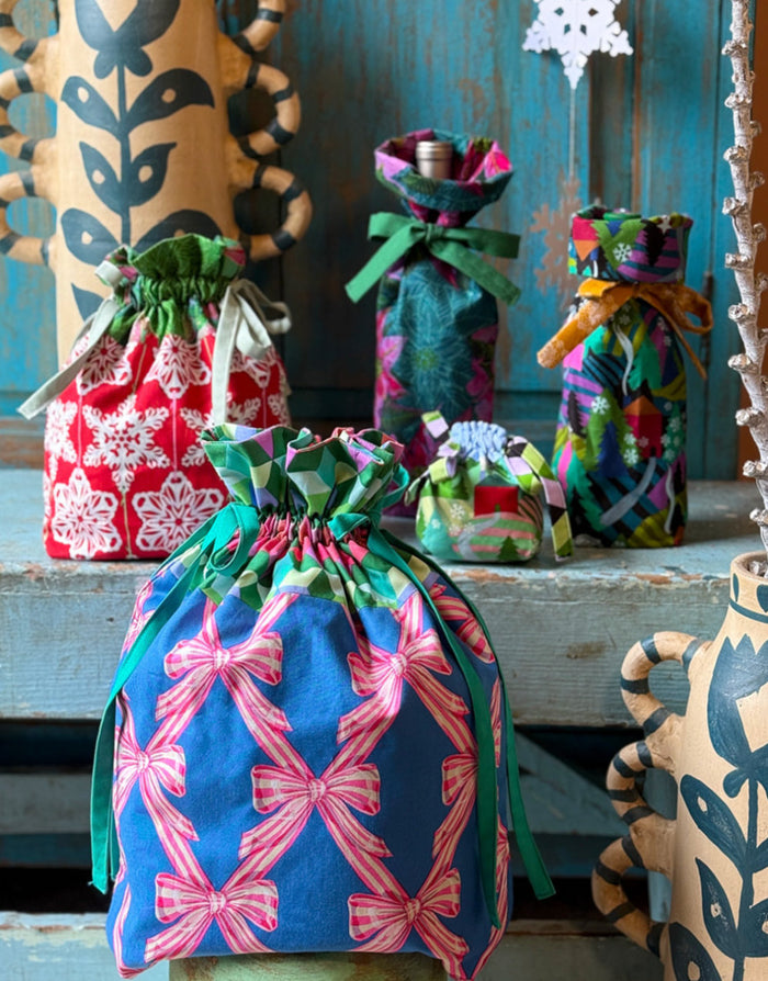 Colorful fabric bags with drawstrings on a rustic wooden surface.