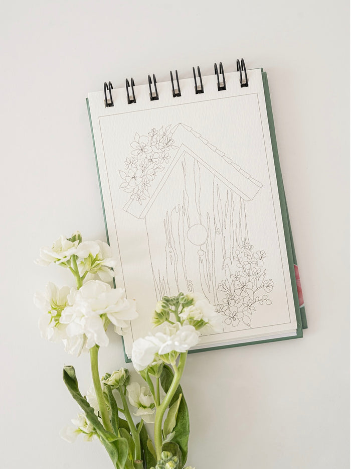 Notebook with architectural drawing and white flowers on a light surface