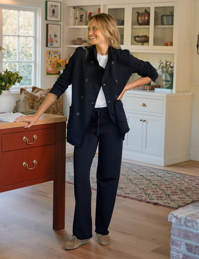 Woman in a navy blue outfit standing in a home interior.