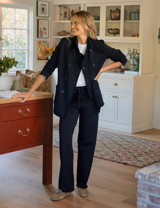 Woman in a navy blue outfit standing in a home interior.