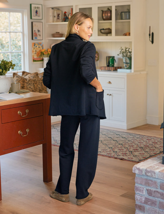 Person wearing a navy suit standing in a home interior.