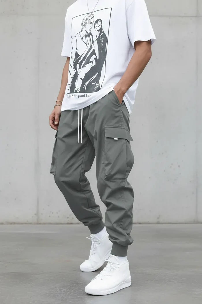 Person wearing a graphic t-shirt, gray cargo pants, and white sneakers against a plain background