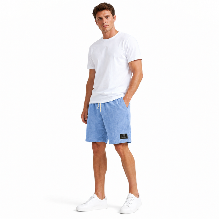 Men's linen shorts styled in a solid color with a loose summer silhouette and embroidered black label detail for beach looks.