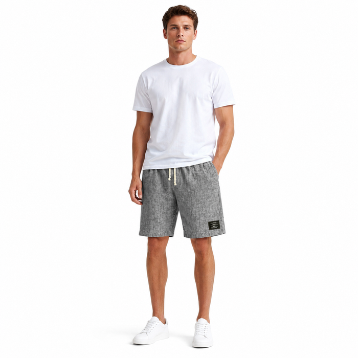 Men's loose linen shorts styled as casual beach pants with a solid color design and clear embroidered black label detail now.