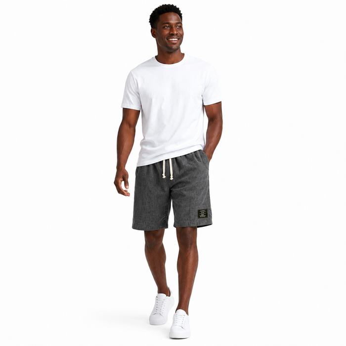 Side angle of men's linen shorts showing the loose summer cut, solid color styling, and stitched black label feature clearly.