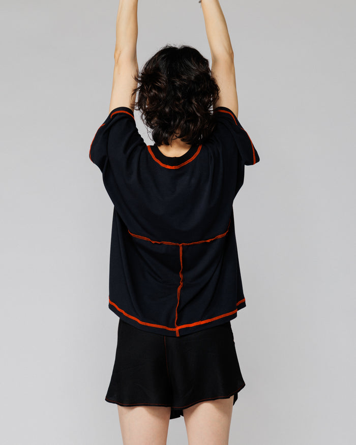 Model with arms raised in Outnback Bog Tee in black, back view showing range of movement