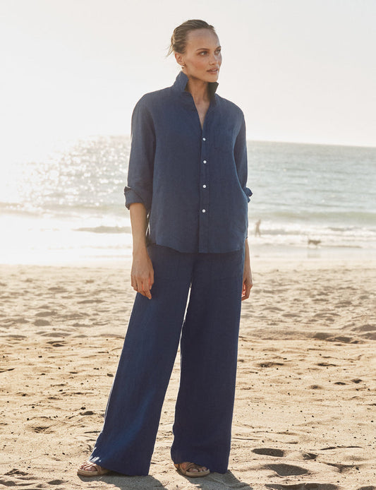 Woman in a navy outfit standing on a beach with ocean in the background