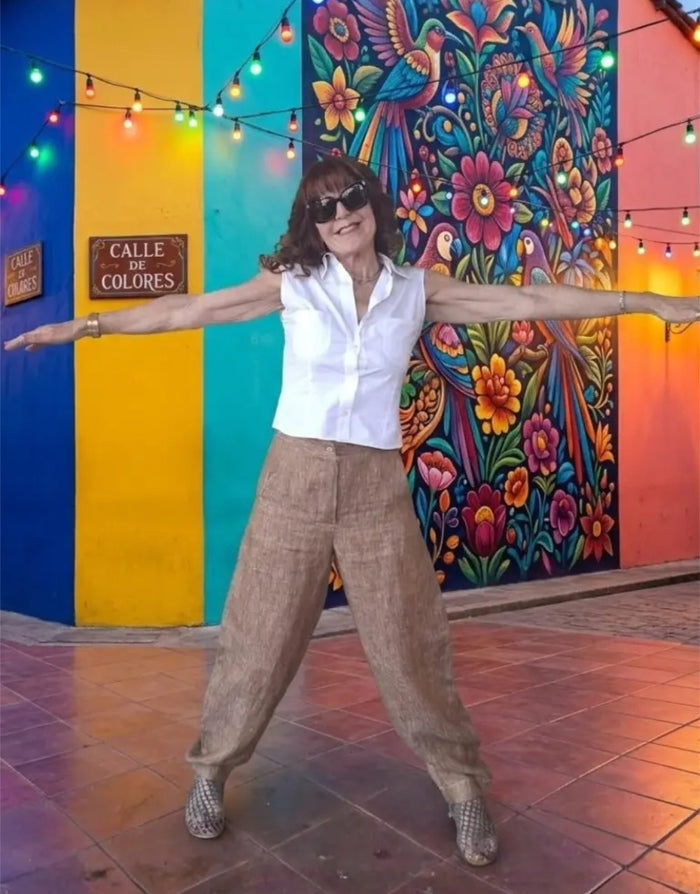 Person posing with arms outstretched in front of a colorful mural with 'Calle de Colores' sign.